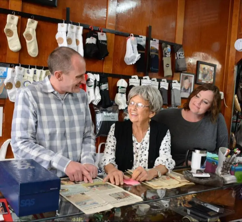 Shirley Eckstein Miller with Jim and Mary at the shop counter on the 100th anniversary